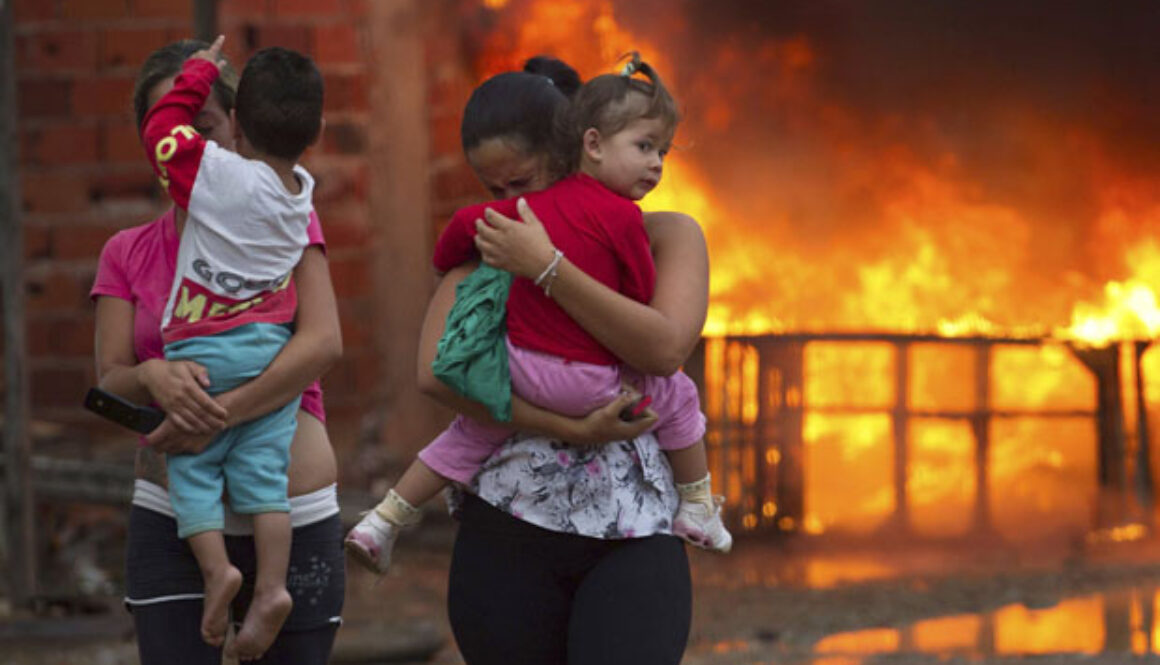 Residents of the Pinheirinho slum walk away from a fire set by other residents resisting police arrival to evict them in Sao Jose dos Campos