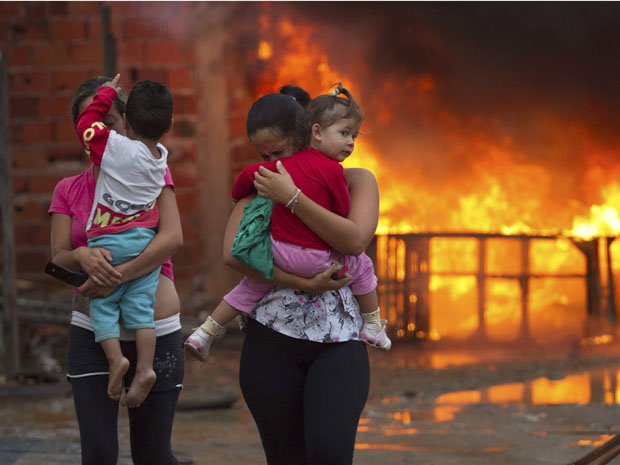 Residents of the Pinheirinho slum walk away from a fire set by other residents resisting police arrival to evict them in Sao Jose dos Campos